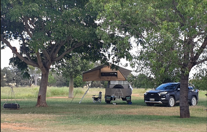 Picture of pop up tent on camper, there is a tyre swing hanging on a tree and there is a nice lawn and plenty of shade.