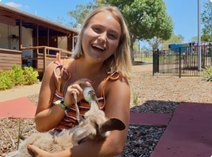 Picture of blond girl enjoying feeding a kangaroo and nursing the joey in a pouch at Myella Farm Stay