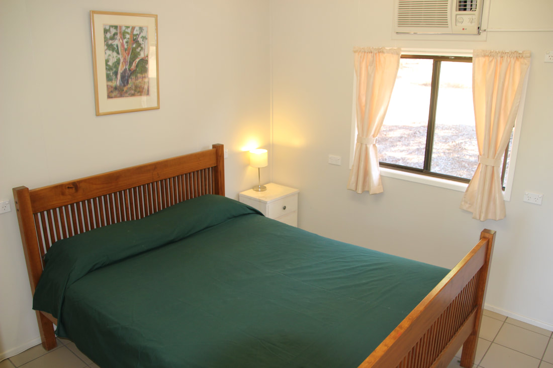Double/single motel style room at Myella Farm Stay has a double bed and ensuite plus a fan, air conditioner, mini fridge, and feature paintings from the Dawson River Artists of Baralaba.