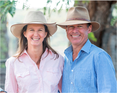 Farm Stay Hosts Lyn Eather and Carl Hendrick standing under a tree in cowboy hats